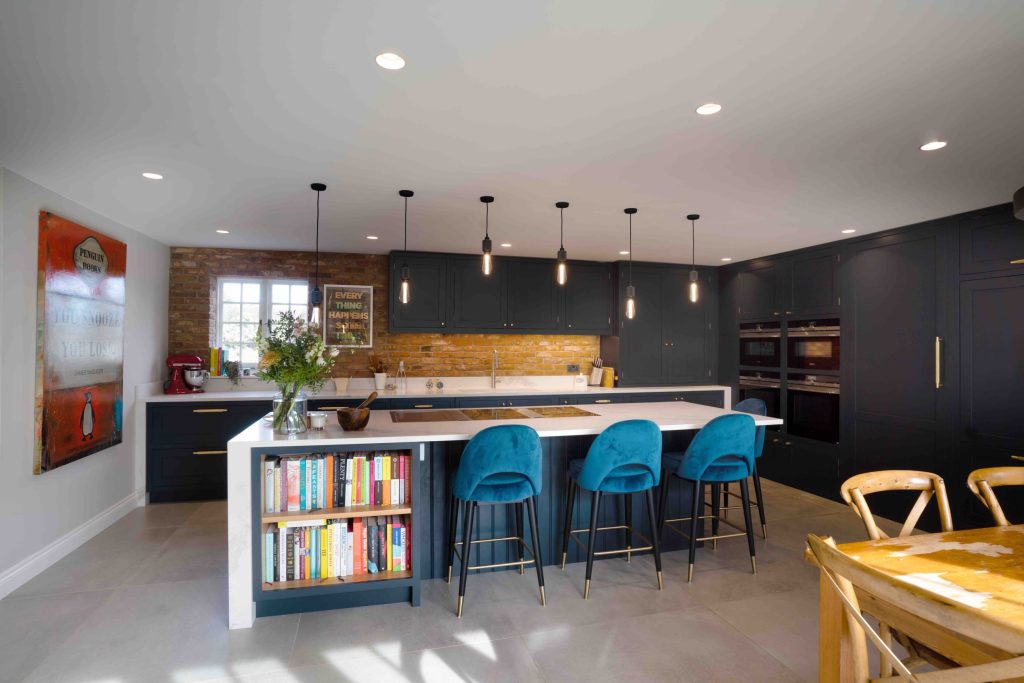 Dark grey kitchen design with teal bar stools and exposed brickwork by The Brighton Kitchen Studio