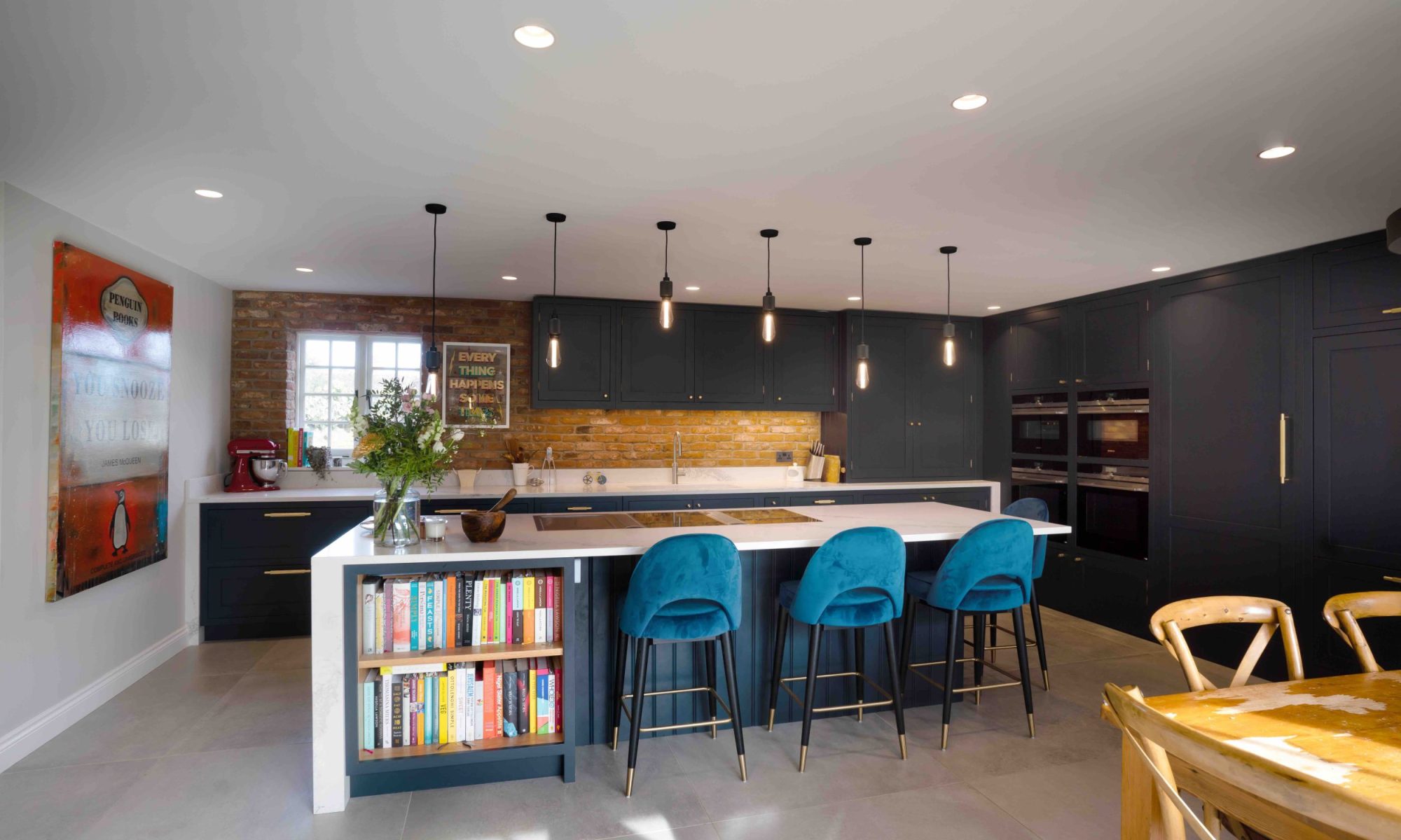 Dark grey kitchen design with teal bar stools and exposed brickwork by The Brighton Kitchen Studio