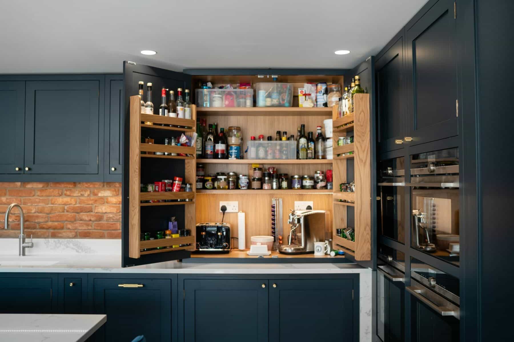 Stylish kitchen with navy shaker cabinets, a marble island, and modern recessed lighting, featuring a coffee machine, spice racks, and a toaster.