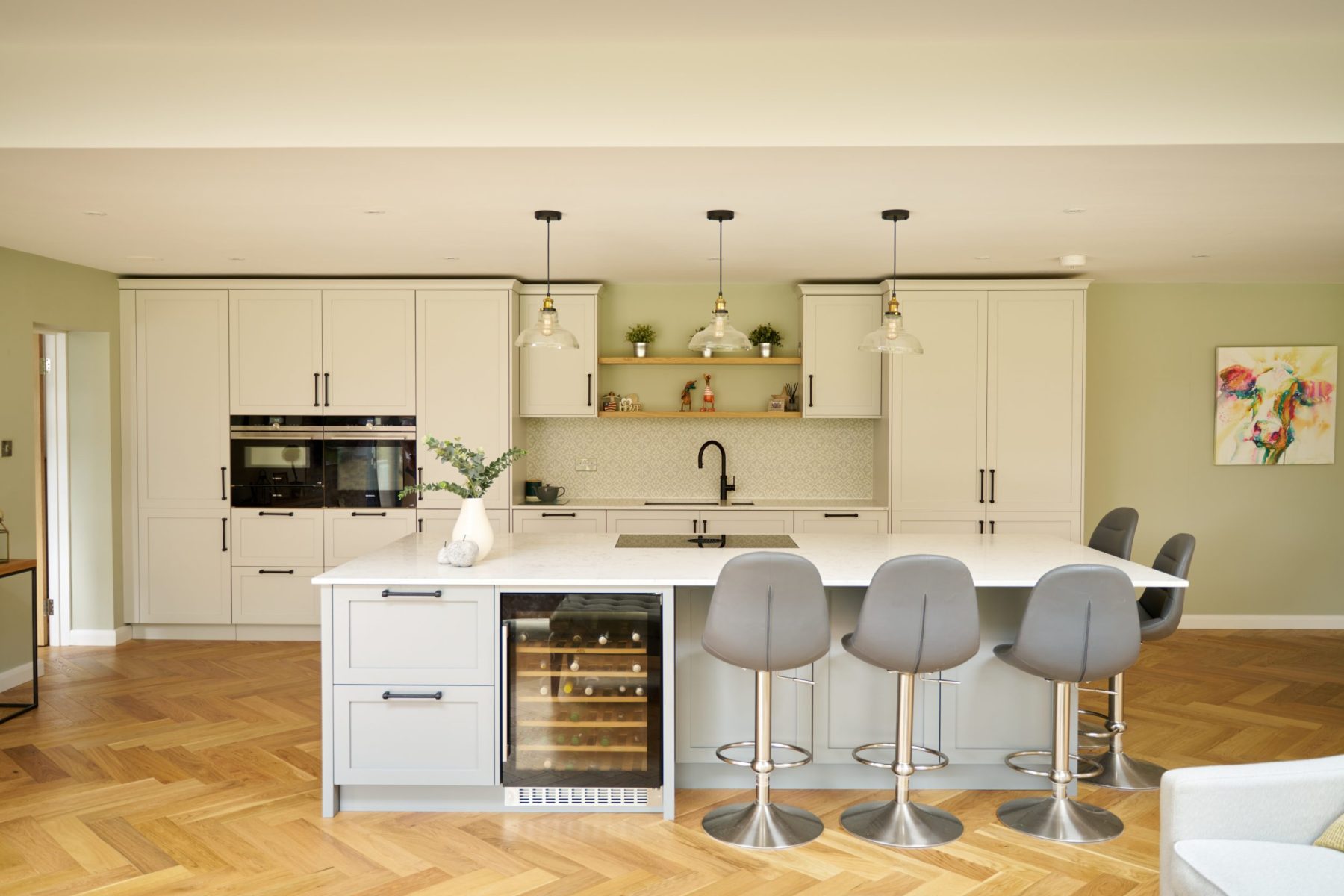 Mixed grey cabinets with kitchen island , integrated wine fridge, grey bar stools oak wood flooring