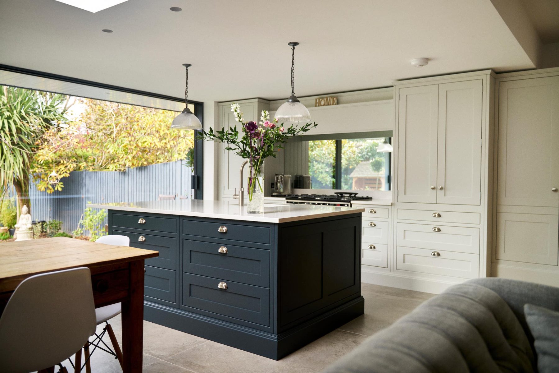 bespoke shaker painted kitchen with dark blue island and soft feature kitchen pendant lighting