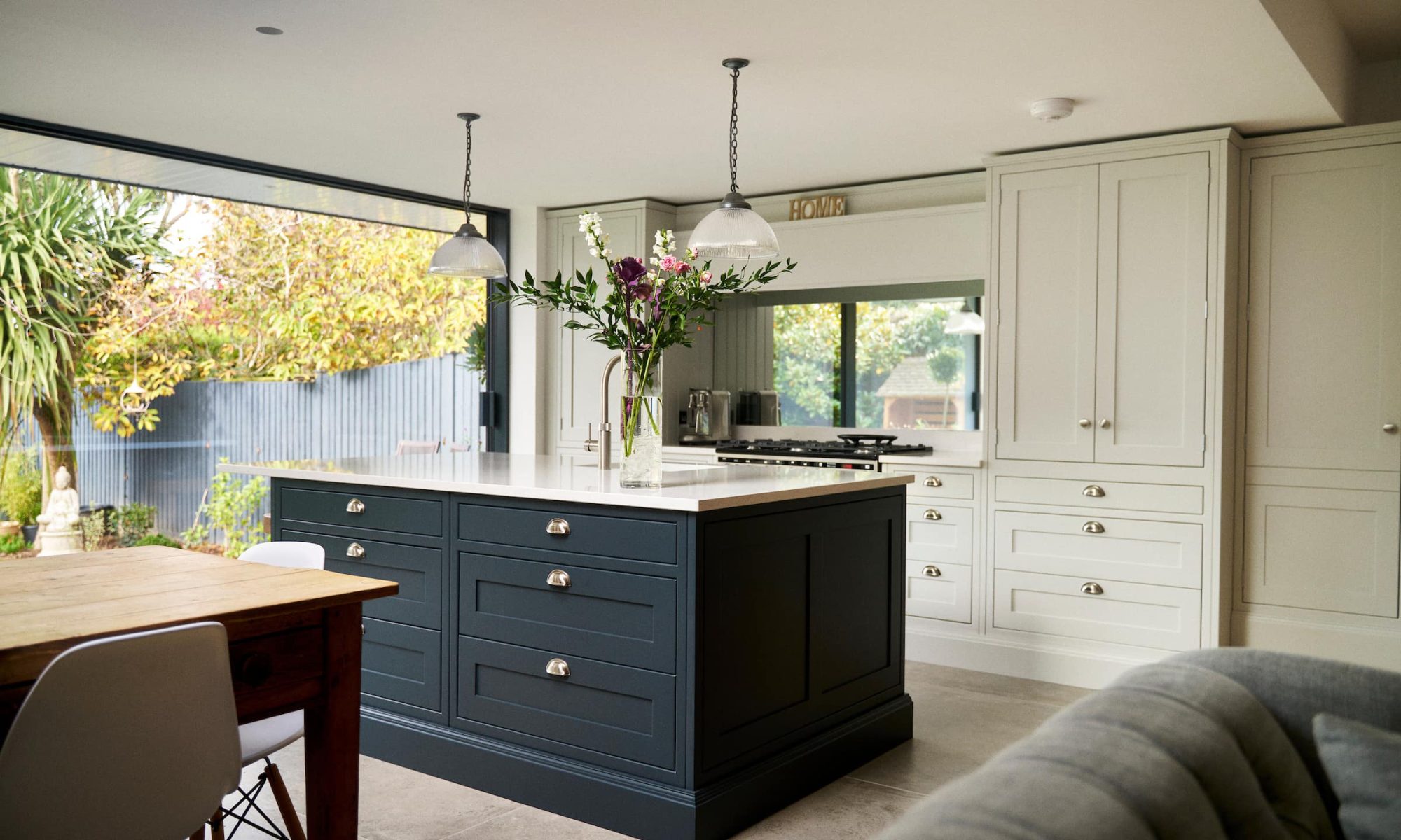 bespoke shaker painted kitchen with dark blue island and soft feature kitchen pendant lighting
