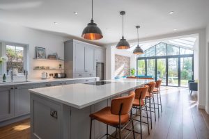Grey sneaker kitchen with island and velvet orange bar stools. Gable end doors and window