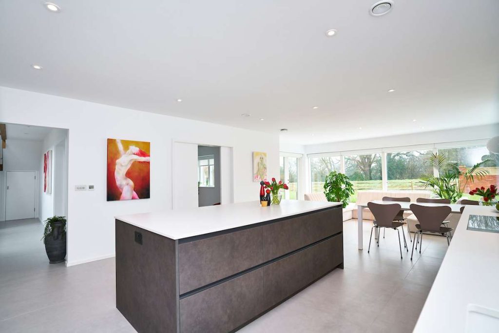 bespoke handleless kitchen with white cabinets and integrated appliances in a modern open-plan space