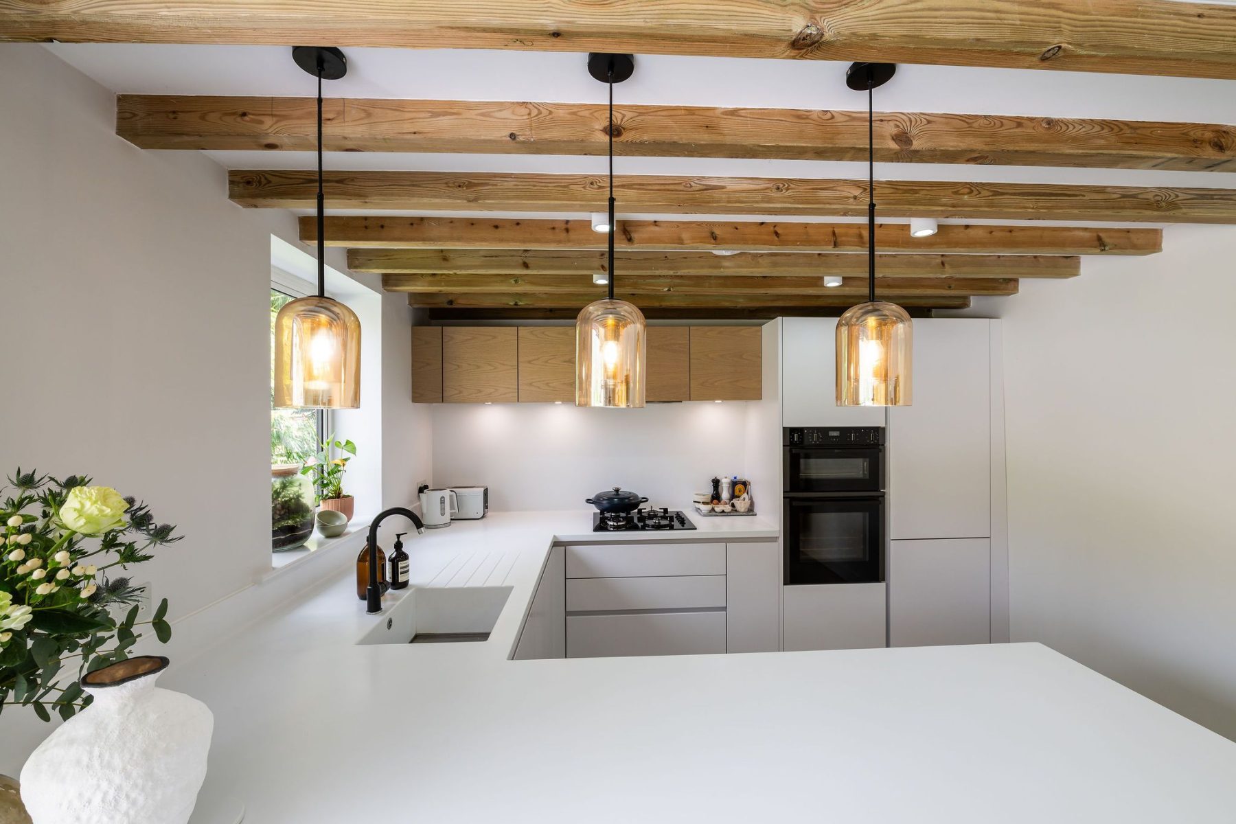 Minimalist white kitchen with soft-close drawers and amber glass pendant lighting