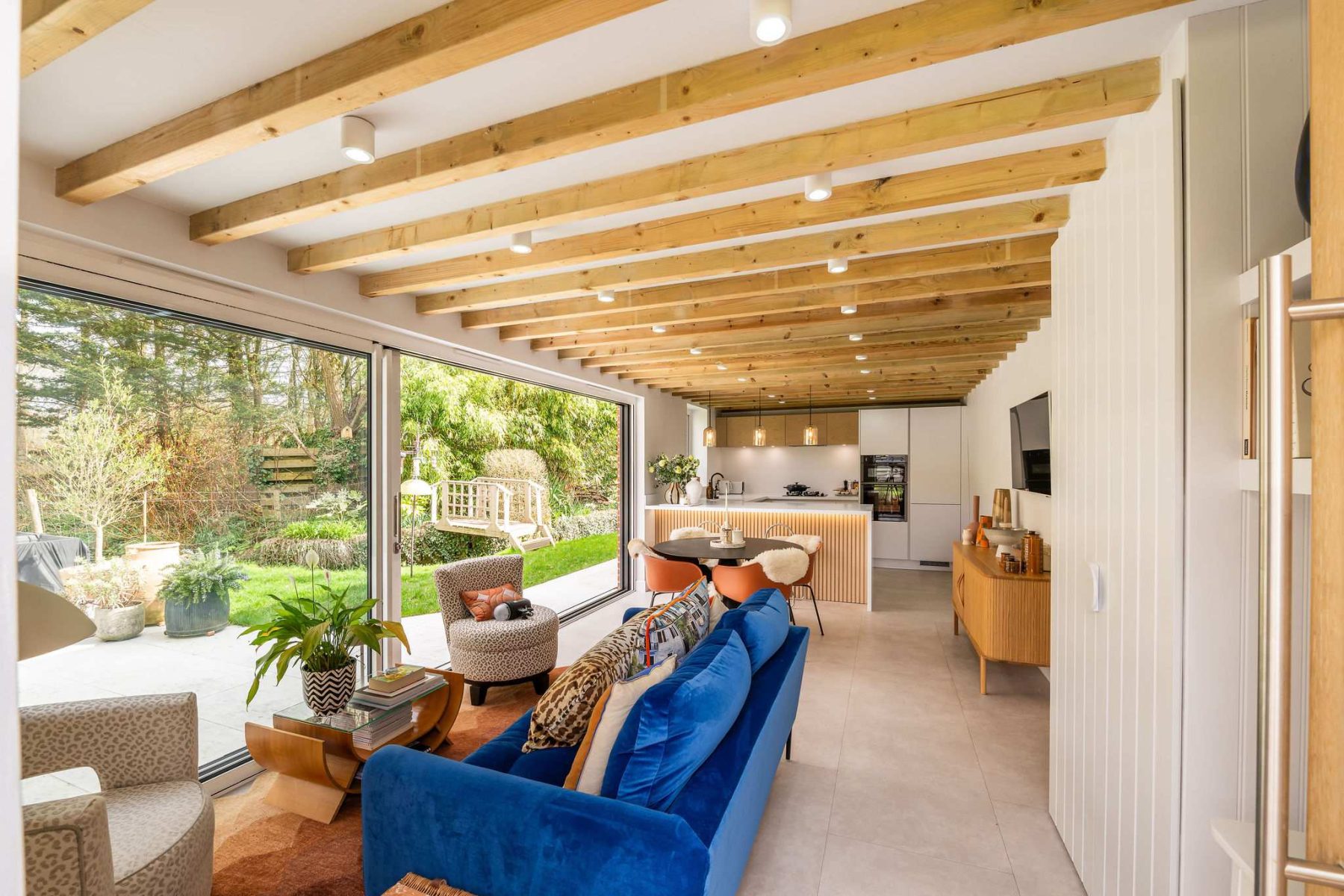 Modern garden room kitchen with bi-fold doors opening to landscaped outdoor space
