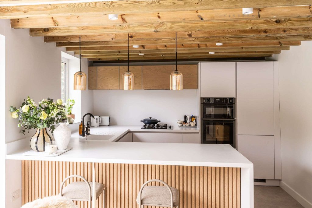Modern handleless kitchen with light wood ceiling beams and minimalist design