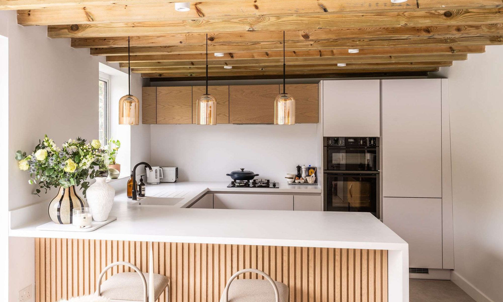 Modern handleless kitchen with light wood ceiling beams and minimalist design