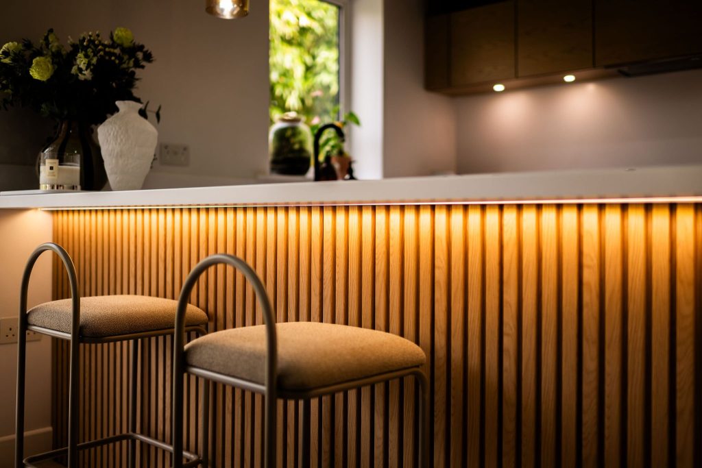Slatted oak breakfast bar with undercounter ambient LED lighting and soft stools