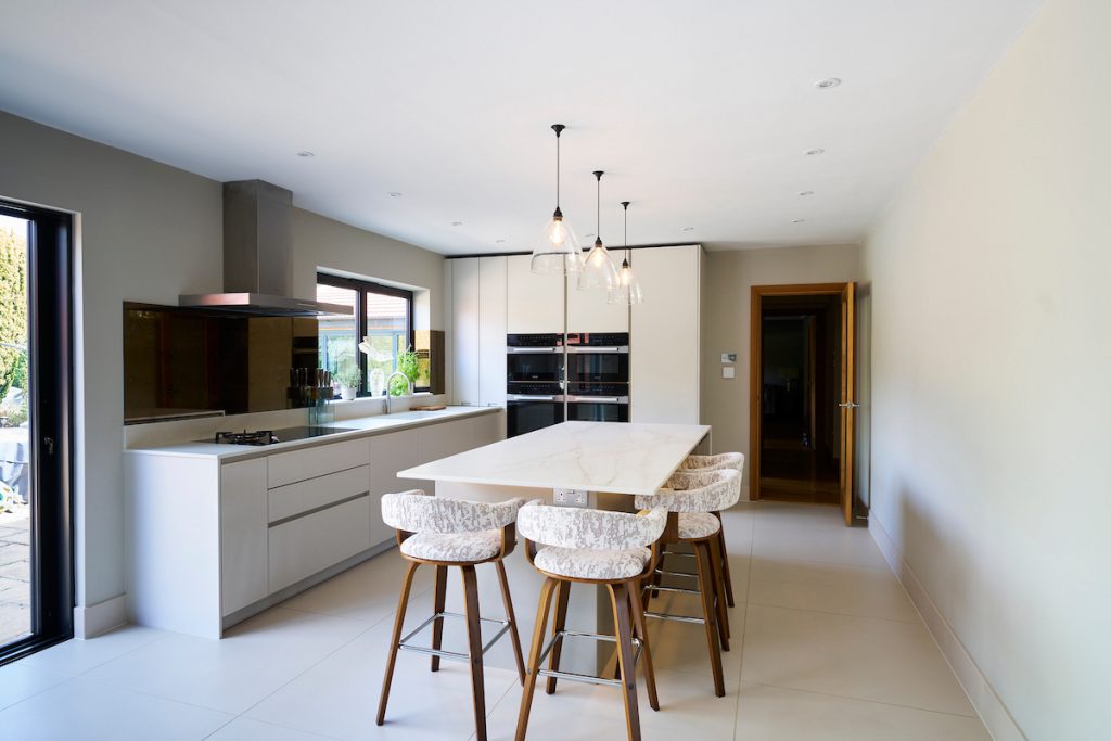 Open plan living space with Breakfast bar Island and warm wood Bar Stools with built in Meile Ovens
