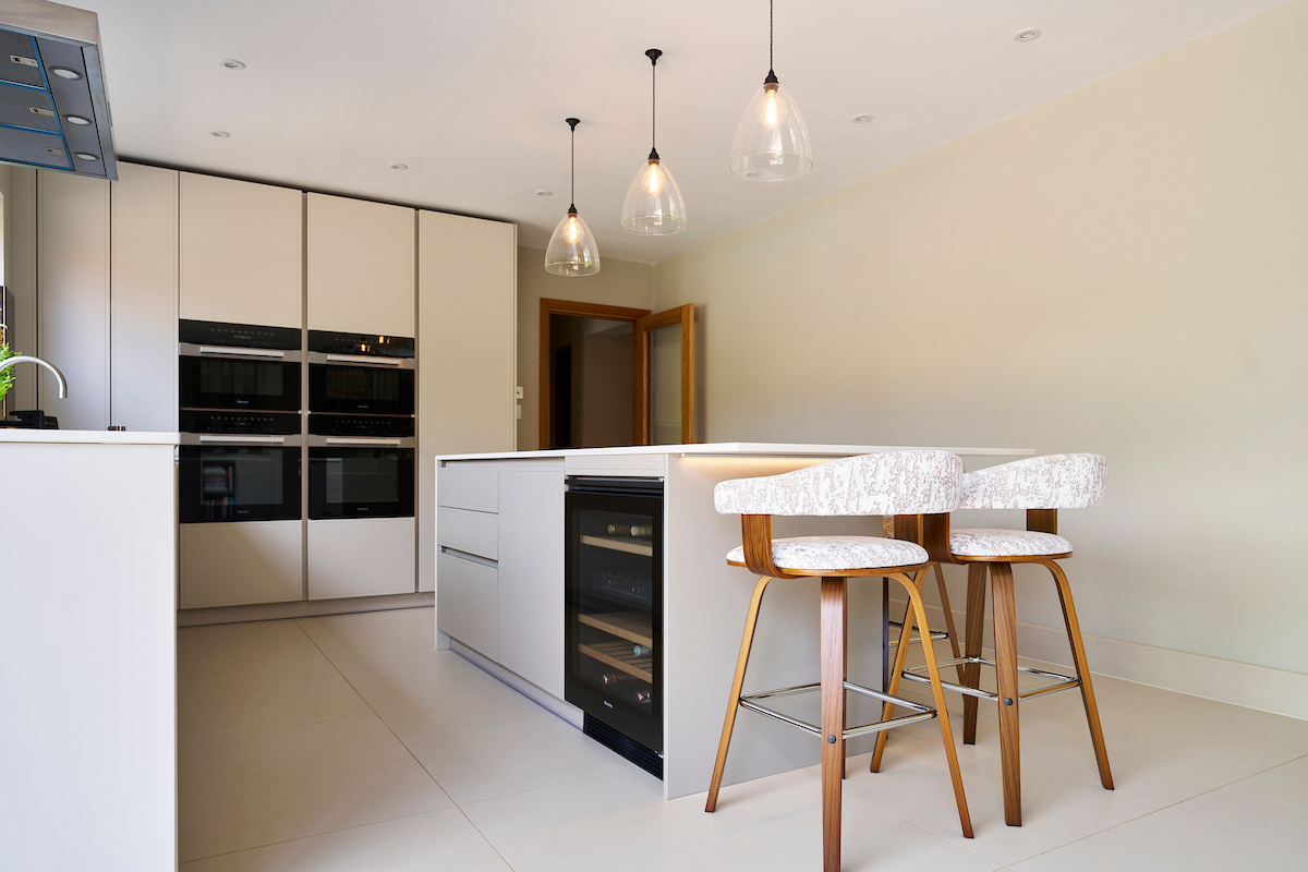 Contemporary marble-effect island with built-in wine cooler and stylish upholstered bar stools.