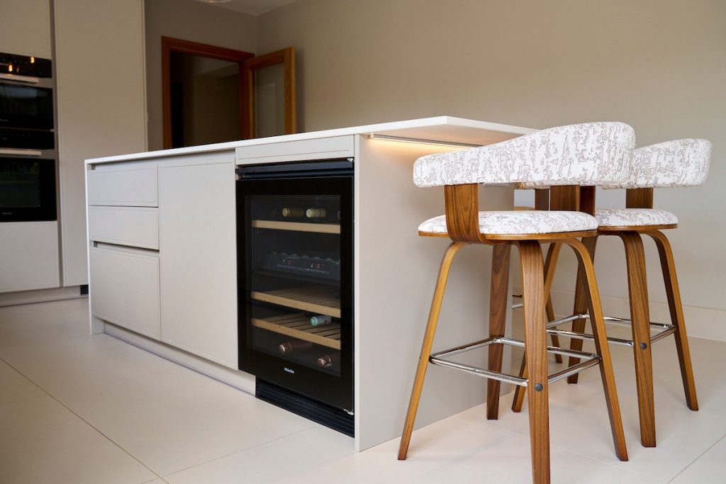 Contemporary marble-effect island with built-in wine cooler and stylish upholstered bar stools.