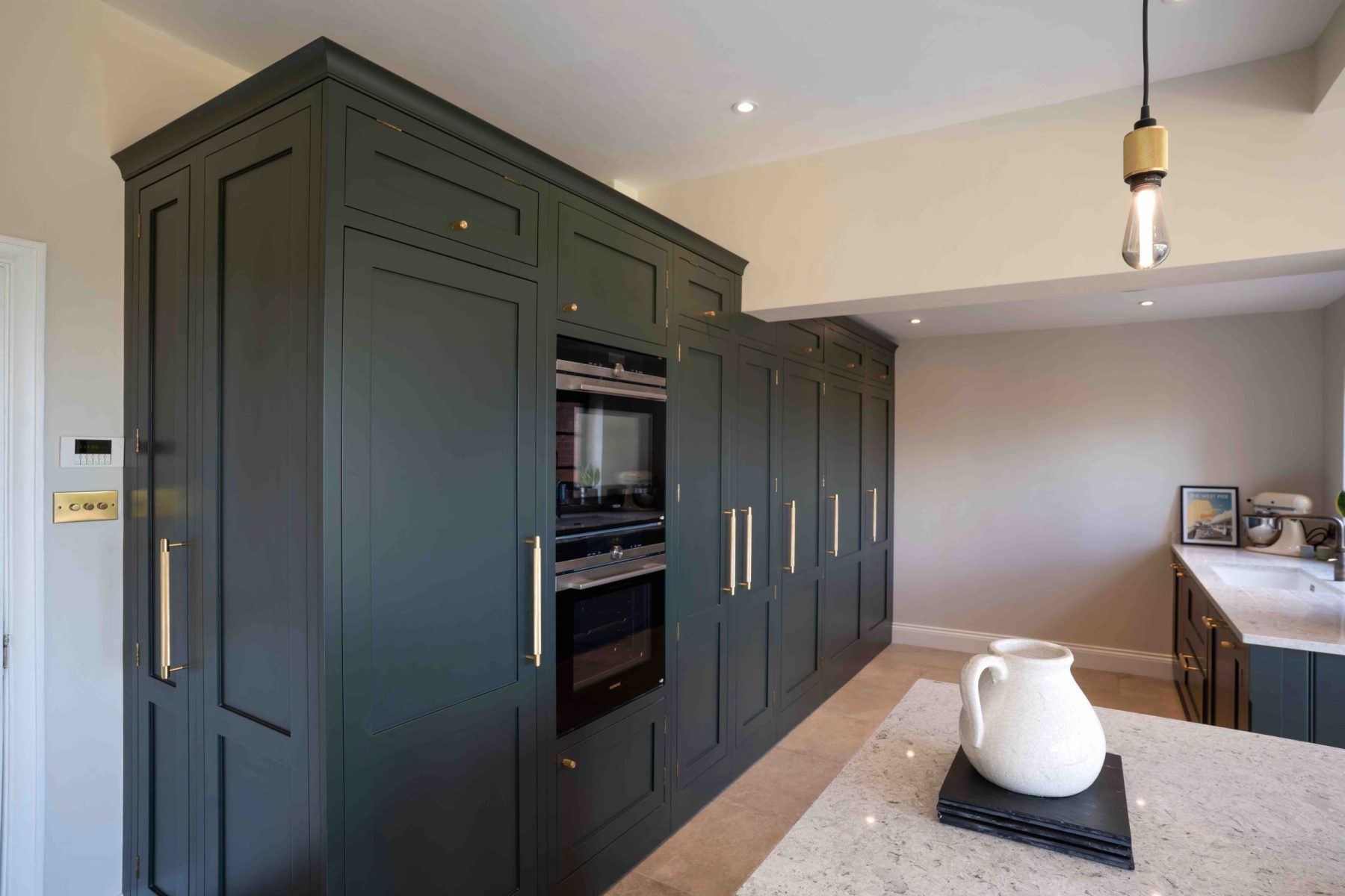 Dark green shaker tower cabinets floor to ceiling with integrated ovens